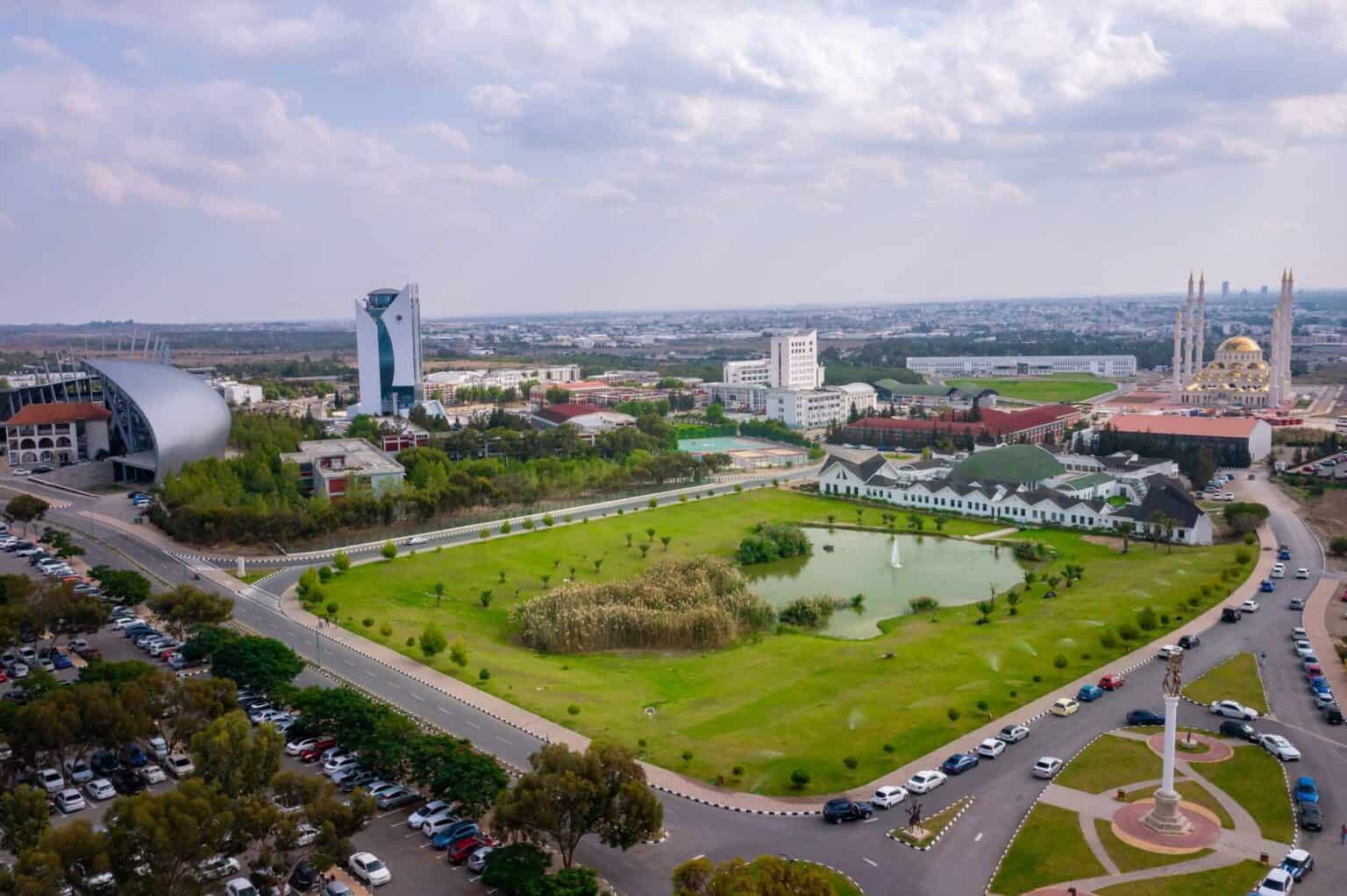 Panoramic aerial view of Near East University campus in North Cyprus showing the grand mosque, science building, amphitheater, green spaces, and academic facilities.