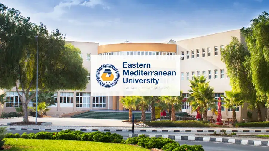 The modern main building and beautiful green campus of Eastern Mediterranean University (EMU) in Famagusta, North Cyprus, under a clear blue sky.