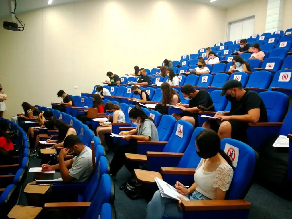 Group of Moroccan students attending class and taking exams in a Near East University lecture hall in North Cyprus, wearing masks and studying.
