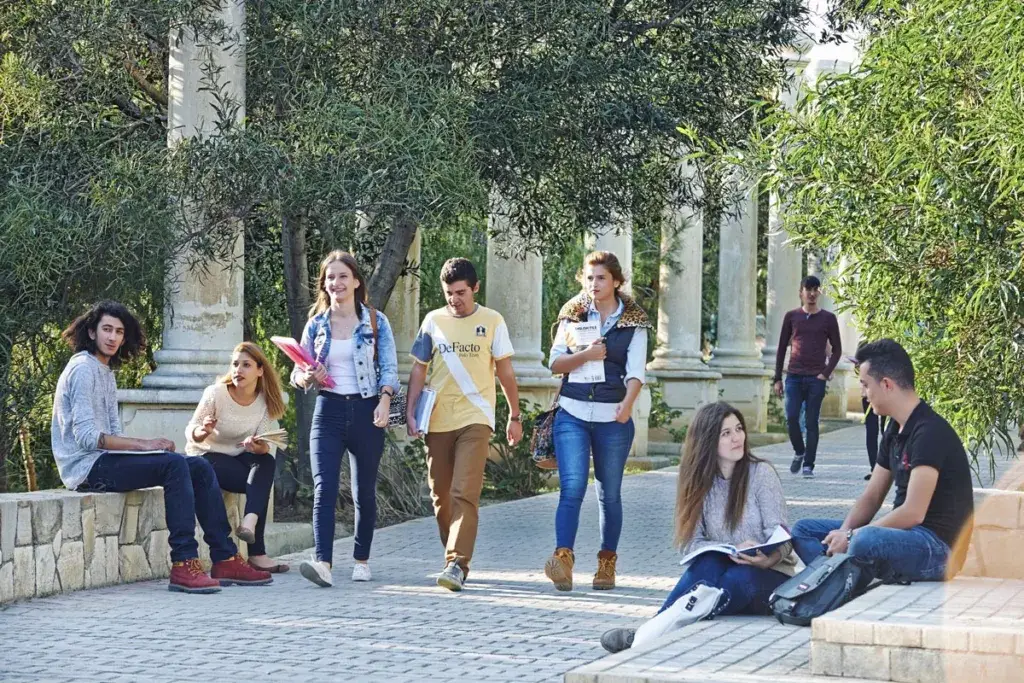 University students in North Cyprus walking and studying on a tree-lined campus path, representing everyday student life and a relaxed study environment.