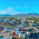 Aerial view of Near East University campus in North Cyprus, featuring modern buildings, green landscape, and surrounding mountains.