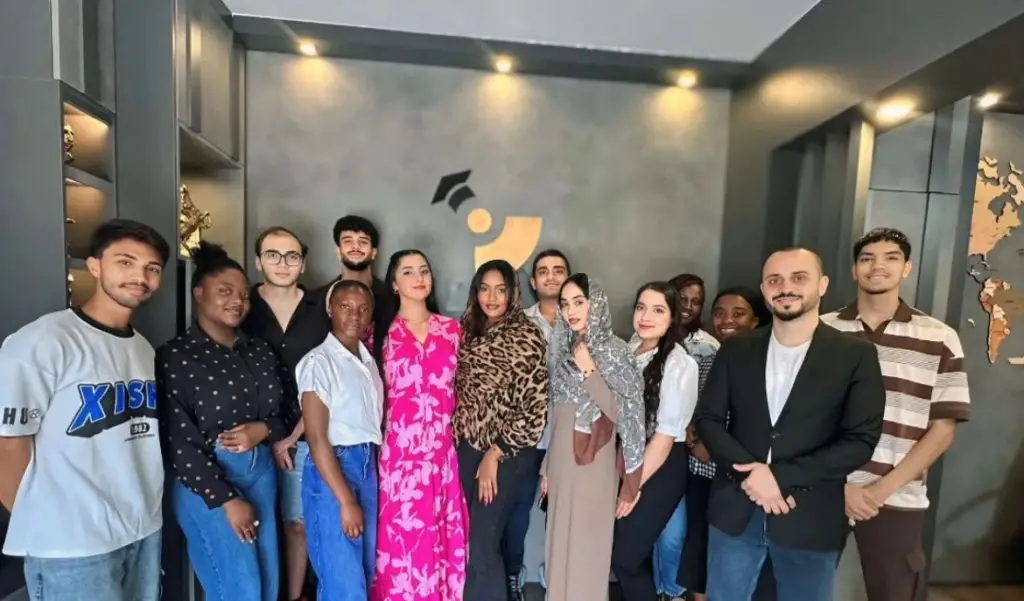 Group of international students from Africa, the Middle East, and Asia standing together in an educational office in North Cyprus, representing multicultural student life.