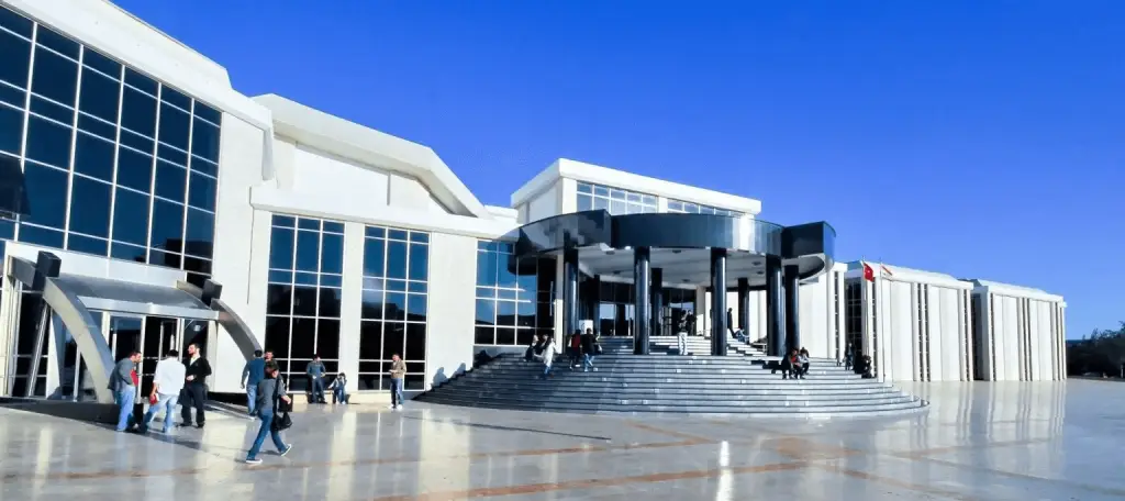 Main entrance of Near East University (NEU) campus in North Cyprus, featuring modern architecture, large glass facade, and students entering the university.