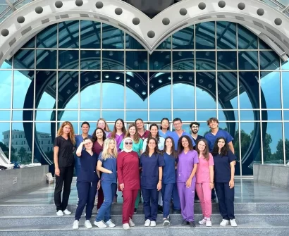 Group of international medical students standing in front of Near East University medical faculty building in North Cyprus, wearing medical uniforms.