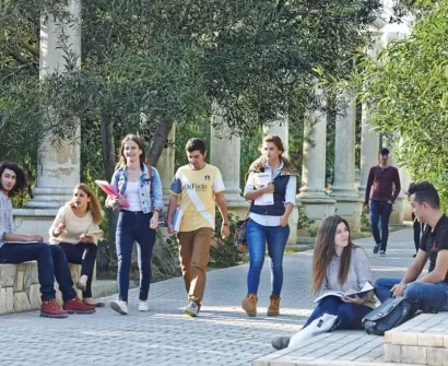 University students in North Cyprus walking and studying on a tree-lined campus path, representing everyday student life and a relaxed study environment.