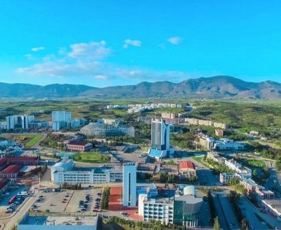 Aerial view of Near East University campus in North Cyprus, featuring modern buildings, green landscape, and surrounding mountains.