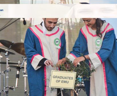Male and female graduates in academic gowns at Eastern Mediterranean University (EMU) in North Cyprus participating in the graduation ceremony planting ritual.
